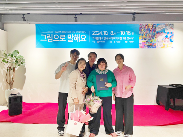 2024년 제5회 자폐성 장애인 그림공모전에서 최우수상을 수상한 홀트강동복지관 홀트강동대학 소속 홍예지 수상자(앞줄 가운데)가 지인들과 함께 기념사진을 찍고 있다.