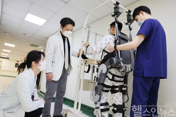가톨릭대학교 여의도성모병원 재활의학과 장소연 교수(좌측)와 원선재 교수(좌측 두 번째)가 보행보조 재활 로봇으로 치료받는 환자의 상태를 살펴보고 있다. (가톨릭대학교 여의도성모병원 제공)