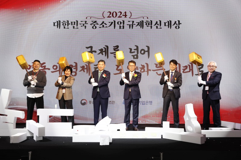 사진은 16일 서울시 중구 더플라자호텔에서 열린 ‘2024 대한민국 중소기업 규제혁신대상’' 시상식에서 김성태 IBK기업은행장(오른쪽 세번째), 최승재 옴부즈만(왼쪽 세번째) 및 수상자들이 '낡은 규제 장벽'을 망치로 부수는 퍼포먼스를 진행하고 있는 모습
