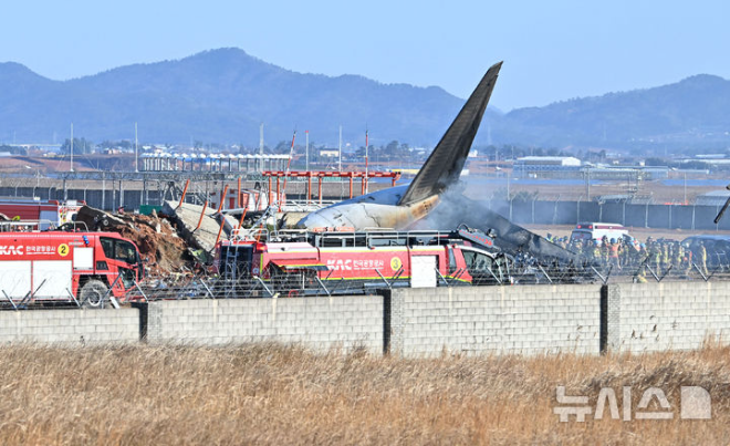 29일 오전 전남 무안공항에서 소방 당국이 착륙 도중 충돌로 추정되는 사고가 난 여객기 주변 화재 현장 구조 활동을 벌이고 있다. (사진 = 뉴시스)
