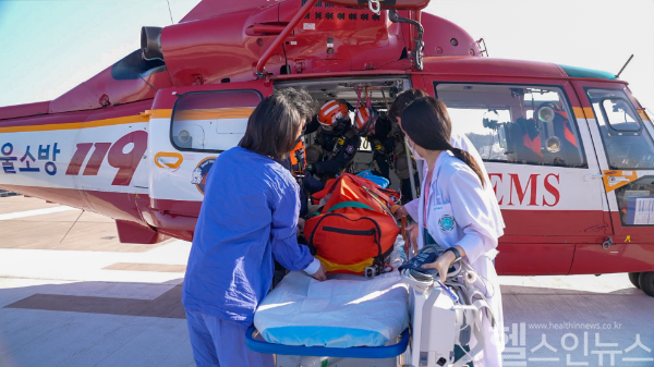 이대서울병원 의료진이 응급환자 이송 전용 엘리베이터를 타고 헬기장에 도착해 구조대원들로부터 환자를 인계받고 있다. (이화의료원 제공)