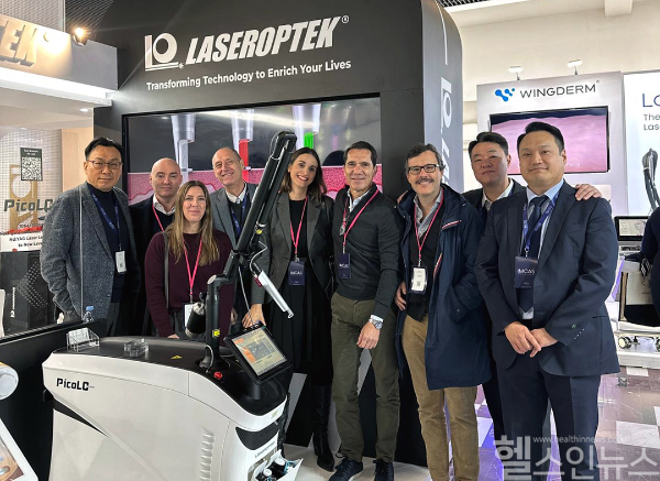 레이저옵텍의 ‘IMCAS 2025’ 전시 부스에서 회사 관계자들이 기념촬영을 하고 있다. (레이저옵텍 제공)