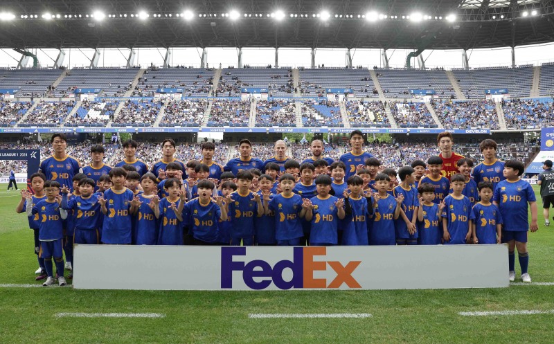 울산 HD FC 유소년 팀 선수들과 플레이어 마스코트가 경기 전 페덱스 로고와 함께 기념 촬영을 하고 있다