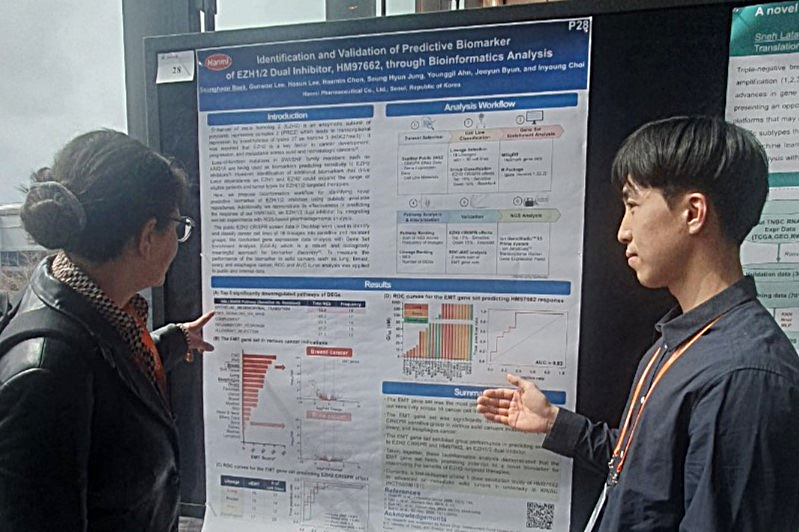 한미약품 R&D센터 백승헌 연구원(오른쪽)이 4월 4일(현지 시각) 열린 ‘2025 Bio-IT World Conference & Expo’에서 차세대 항암 신약 ‘EZH1/2 이중 저해제(HM97662)’의 주요 연구 내용이 담긴 포스터를 토대로 참석자에게 설명하고 있다. 〈사진제공=한미약품〉