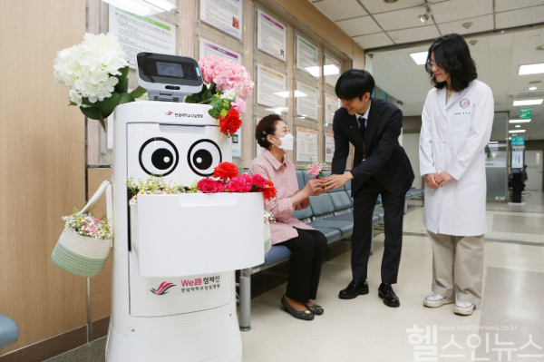 8일 어버이날을 맞아 한림대성심병원 직원들이 물품을 나르는 배송로봇 ‘나르미’룰 활용해 어르신 방문객에게 카네이션을 전하고 있다. (한림대성심병원 제공)