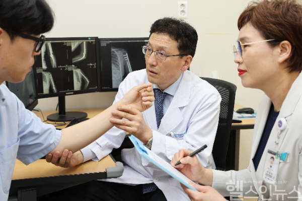 전인호 서울아산병원 정형외과 교수(가운데)가 환자가 직접 평가하는 통증 정도를 확인하며 환자 건강상태 자가평가(PROMs)를 진행하고 있다. (서울아산병원 제공)