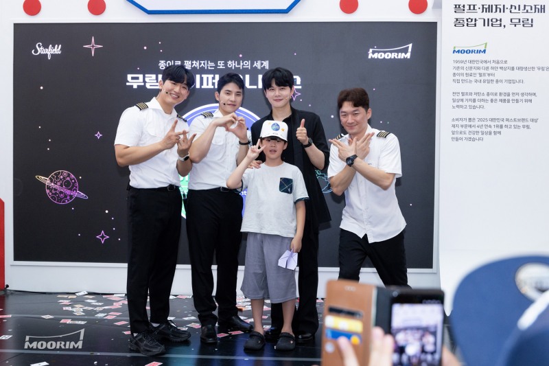 ‘페이퍼어드벤처 2025 – 무림페이퍼 유니버스’에서 합동 공연을 마친 종이마술사 ‘니키’, 종이비행기 국가대표팀 ‘위플레이’와 함께 포토타임을 즐기는 어린이 관람객 / 사진제공=무림