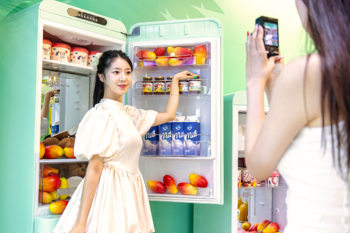 ‘망빙고 가챠샵’ 내 셀피존에서 방문객이 애플망고와 ‘애망빙’ 제품이 진열된 냉장고를 배경으로 기념사진을 촬영하고 있다.