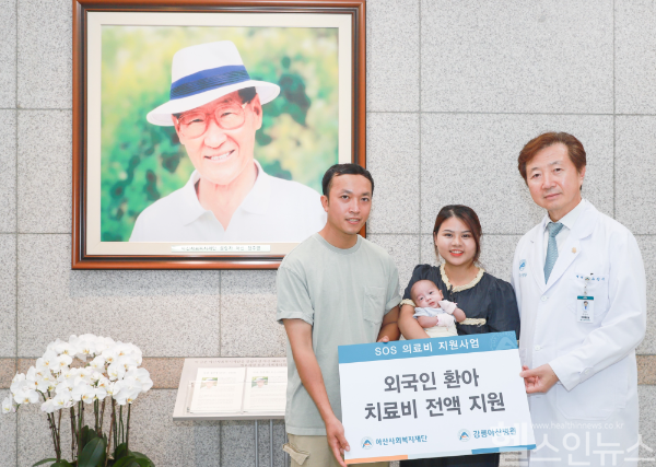 유창식 병원장과 환아의 가족이 고(故) 정주영 아산사회복지재단 설립자의 사진 앞에서 기념촬영을 하고 있다. (강릉아산병원 제공)