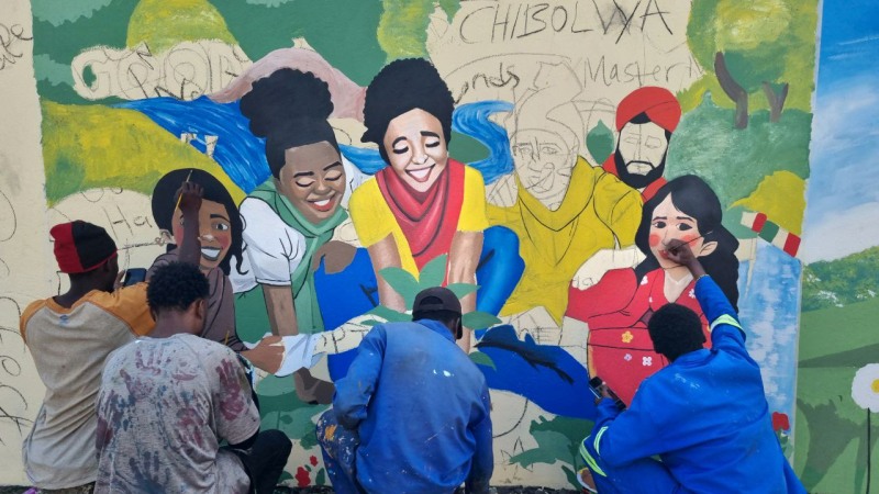 지난 11일 잠비아 루사카 치볼야 지역에서 진행된 '청년과 타 종교 간 벽화 봉사'에서 자원봉사자들이 벽화를 그리고 있다. (사진 제공 = HWPL)