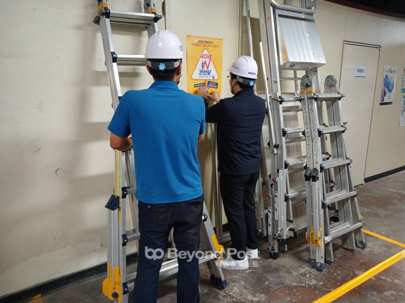 안전보건공단 서울남부지사 관계자(오른쪽)가 소규모 건물관리 현장 사다리 보관 장소 벽면에 '사다리 N 안전모' 홍보 포스터를 부착하고 있다./신용승 기자