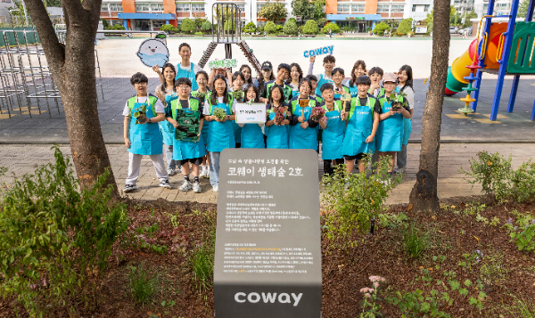 코웨이 임직원과 방화초 학생들이 코웨이 생태숲 2호 현판 앞에서 기념 촬영을 하고 있다.