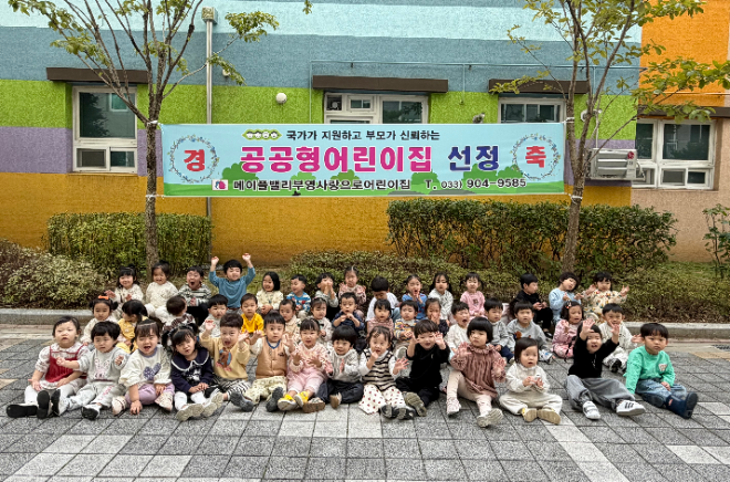 원주 '메이플밸리 부영 사랑으로 어린이집' 원생들이 공공형어린이집 선정 현수막 앞에서 해맑게 미소를 지으며 사진을 찍고 있다. ⓒ 부영그룹
