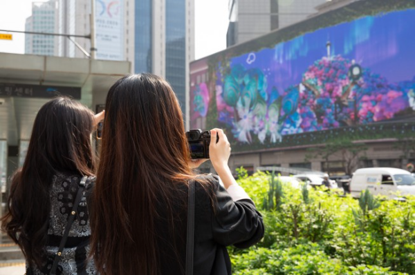 시민들이 도재인, 이뿌리, 하지수 작가의 3D 아나모픽 미디어아트 작품 ‘남산숨길(Namsan Breeze)’을 사진으로 담고 있다.