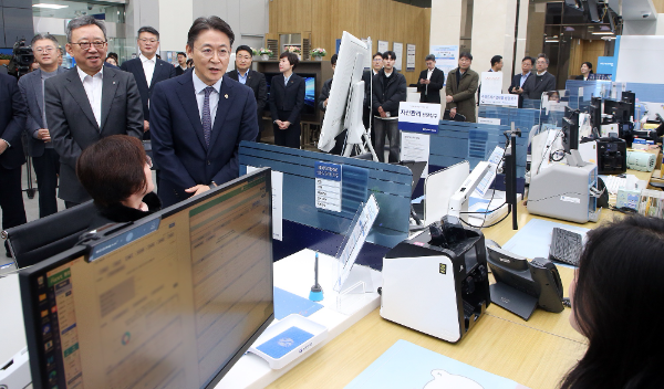 19일 서울시 중구 소재 신한은행 광교영업부에서 진행된 '오프라인 오픈뱅킹·마이데이터 서비스 시연행사'에서 정상혁 신한은행장(뒷편 왼쪽)과 금융위원회 권대영 부위원장(오른쪽)이 서비스에 대한 직원설명을 듣고 있다.