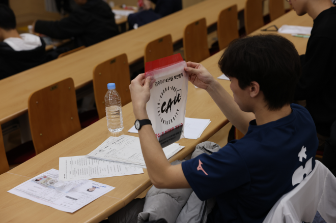 중앙대는 논술고사 시 전자기기 보관용 보안봉투를 통해 전자기기 사용을 미연에 방지한다. 논술고사에 참여한 수험생이 안내에 따라 전원을 끈 전자기기를 보안봉투에 넣고 있다. (사진제공=중앙대)