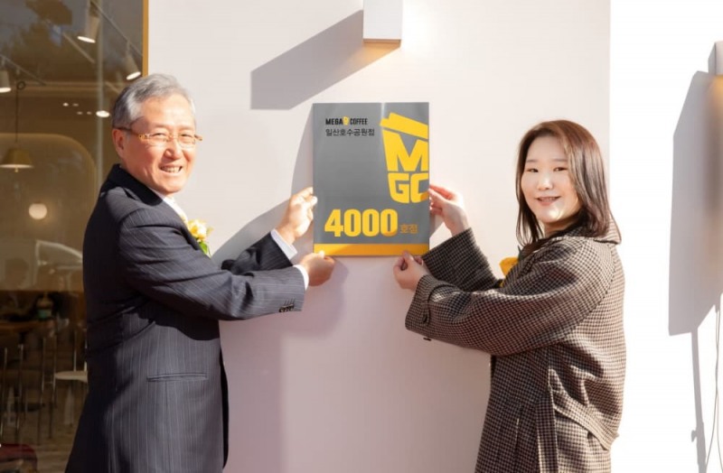 (▲ 메가MGC커피 김대영 대표이사(사진 왼쪽)와 일산호수공원점 안수현 점주(오른쪽)가 지난 달 28일, 4,000호점 오픈 현판식을 갖고 기념 촬영을 하고 있다.