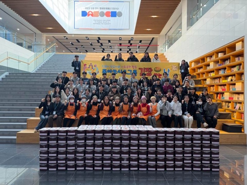 동아쏘시오그룹 사랑의 김장 나눔 봉사활동에 참여한 신입사원과 관계자들이 직접 담근 김치통 뒤에서 밝은 미소를 지으며 기념 촬영을 하고 있다. 이날 만든 김치들은 지역 사회 이웃에게 전달되어 따뜻한 겨울나기를 도울 예정이다.