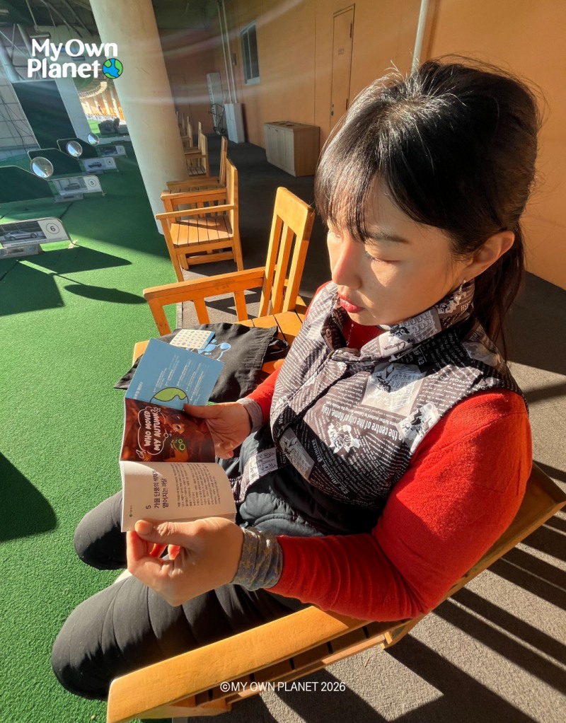 (사진 설명: 골프 연습장에서 ‘마이 오운 플래닛’의 미니북을 읽고 있는 황아름 프로)