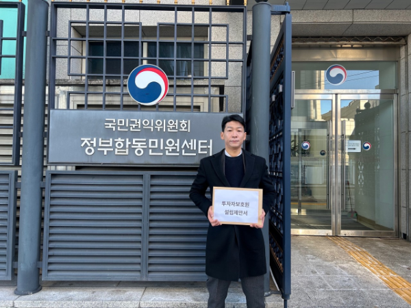 ▲정부합동청사 앞 투자자보호연합회장이 제안서를 들고 있다. (투자자보호연합회 제공)