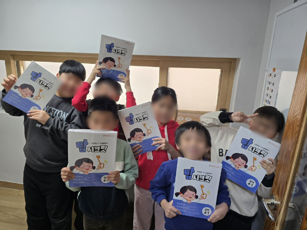 구립석관동꿈나무키우미 돌봄센터 아동들이 초등 교재를 받고 기념촬영을 하고 있다