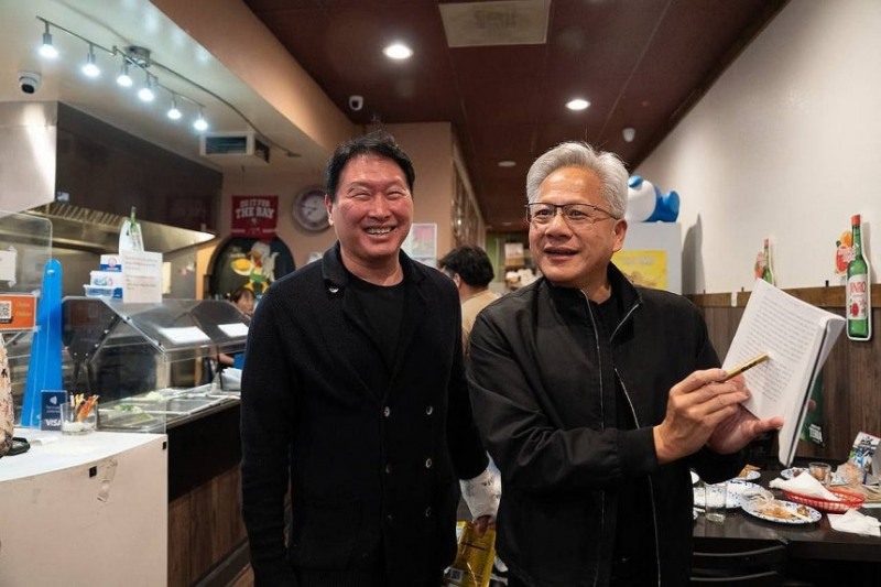 미국 캘리포니아 산타클라라의 한국식 호프집 '99치킨'에서 가진 최태원 SK그룹 회장과의 만찬회동에서 젠슨 황 엔비디아 최고경영자가 신간 '슈퍼모멘텀'을 펼쳐보이고 있다. 2026.2.11