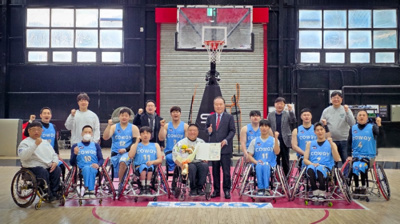 지난 5일 한국휠체어농구연맹 안병태 총재가 코웨이 블루휠스 연습구장을 찾아 김영무 감독에게 표창과 꽃다발을 전달했다. 안병태 총재와 김영무 감독, 코웨이 블루휠스 선수들이 함께 기념사진을 촬영하고 있다.