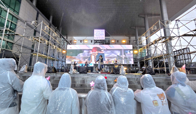 가톨릭관동대학교 마리아관 중앙현관 특설무대에서 진행된 행사에 관람객들이 우비를 입고 관람하고 있는 모습. (사진제공=가톨릭관동대)