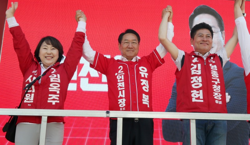 유정복 인천시장 후보가 25일 중구 영종도 운서역 유세 현장에서 김정헌, 임옥주 후보와 손을 맞잡고 시민들에게 인사하고 있다./정복캠프