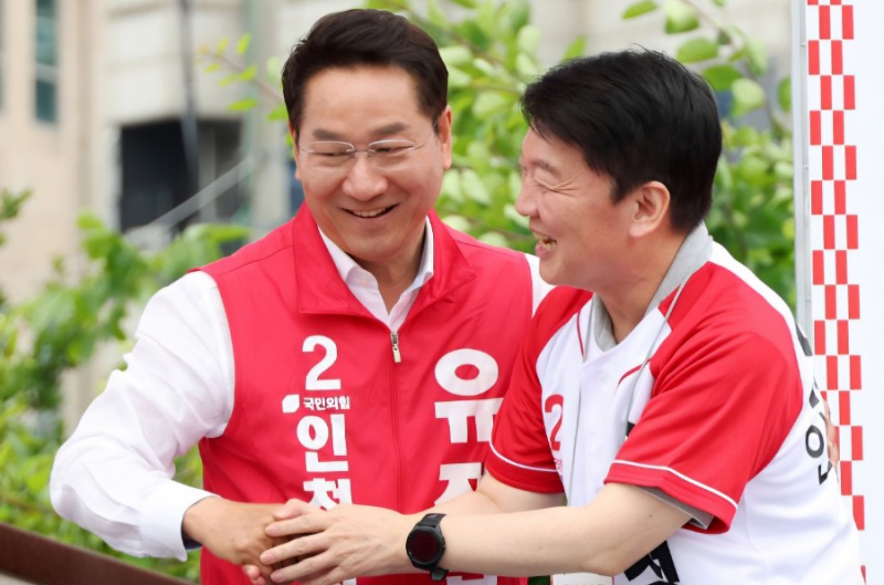 유정복 인천시장 후보가 27일 강화군 풍물시장 유세 현장에서 국민의힘 안철수 의원이 유세차에 올라오자 반갑게 악수하고 있다. /정복캠프