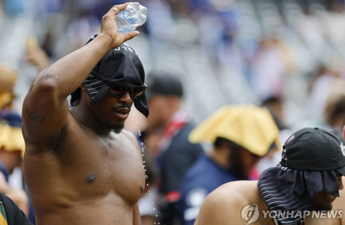 더위를 피해 머리에 물을 뿌리는 축구 팬. / 사진=연합뉴스
