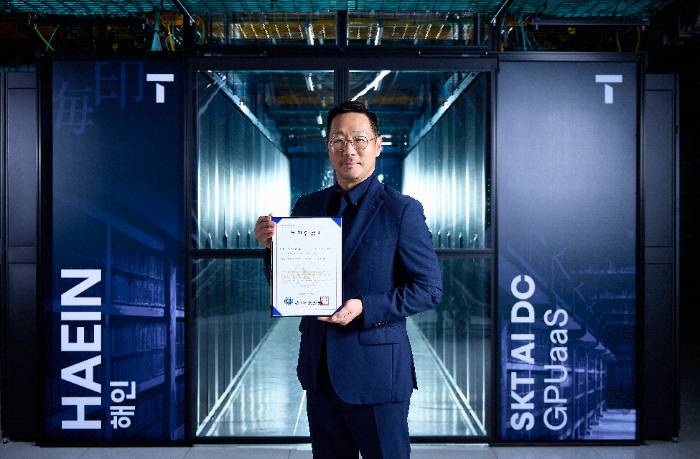 해인 클러스터 앞에서 SKT 김명국 AI Factory 사업담당이 CSAP 인증서를 들고 포즈를 취하는 모습./SKT