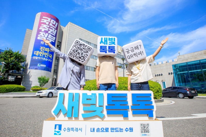 수원시 관계자들이 수원시청 청사 앞에서 새빛톡톡을 홍보하는 사진을 찍고 있다./수원시