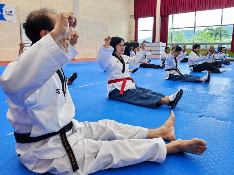 무주군보건의료원은 경락품세 교육 참여자의 신체·정서·인지 건강상태를 살피고, 위험 신호가 확인될 경우 진료와 관련 보건사업으로 연계하는 예방 중심 건강관리 체계를 구축하고 있다. 지난 7월 28일 전북 무주국민체육센터에서 '무주 태린이문화 페스타 경락품세 교육'에 참여한 어르신들이 바닥에 앉아 호흡과 상체 동작을 반복하고 있다. 사진=세계어린이태권도연맹 제공