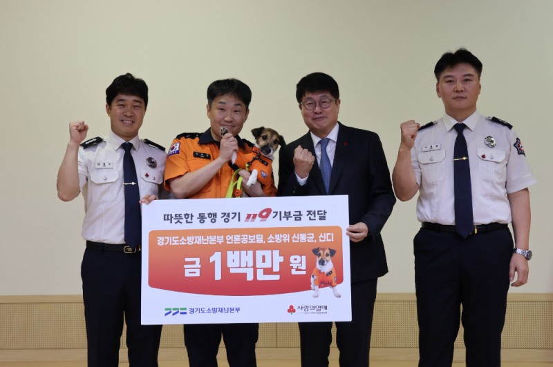 (왼쪽 두 번째부터) 신동균 소방위와 반려견 신디, 권인욱 경기 사랑의열매 회장과 경기도소방재난본부 언론공보팀 직원들이 기부금 전달 후 기념 촬영을 하고 있다.