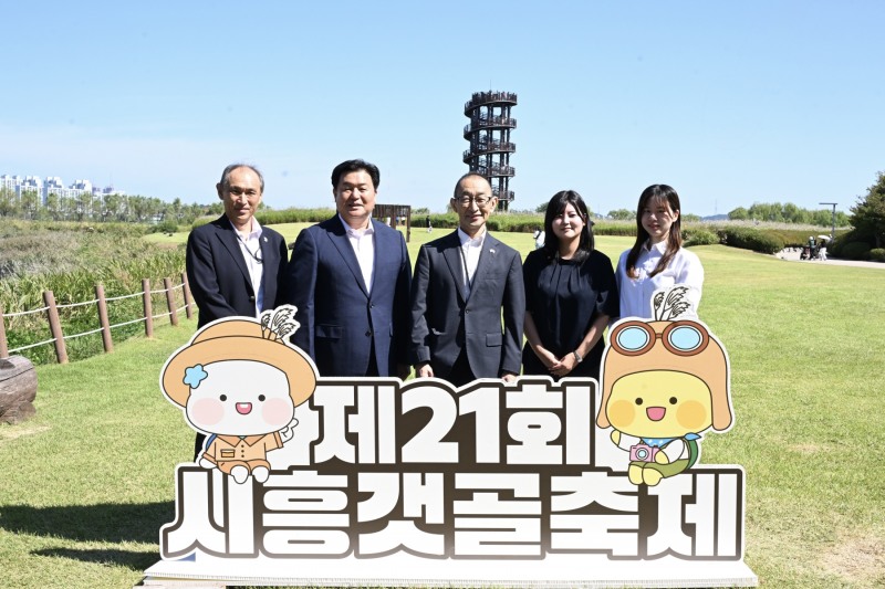 20일 하치오지시 대표단이 갯골축제가 열린 갯골 생태공원을 방문해 흔들전망대를 배경으로 기념 촬영을 하고 있다. (사진 왼쪽에서 두 번째가 임병택 시흥시장, 사진 가운데가 나카무라 히토시 하치오지시 부시장)./시흥시