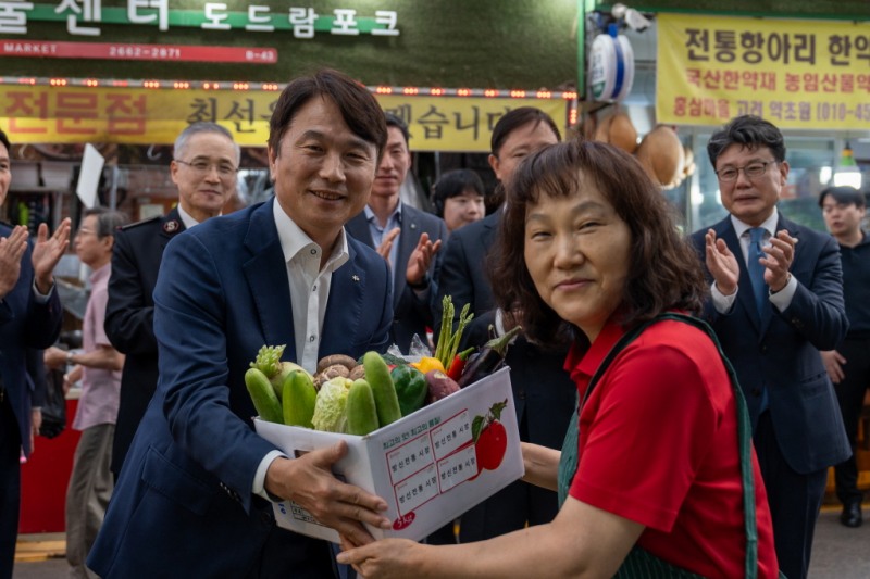 KB손해보험 구본욱 사장(왼쪽)이 18일 서울 강서구 방신전통시장에서 열린 '추석맞이 전통시장 사랑나눔 행사'에 참석해 온누리상품권으로 구매한 명절 용품을 전달받고 있다./KB손해보