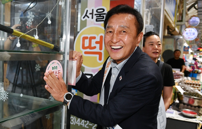 김세훈 화천군수가 지난 8월, 기본소득 첫 지급일에 화천시장 상점에 가맹점 스티커를 부착하고 있다