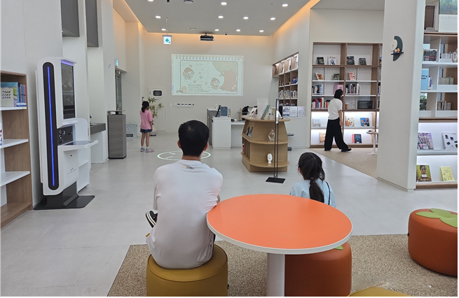 목감작은도서관에서 함께 아트월 상시전시를 보는 부녀. /시흥시