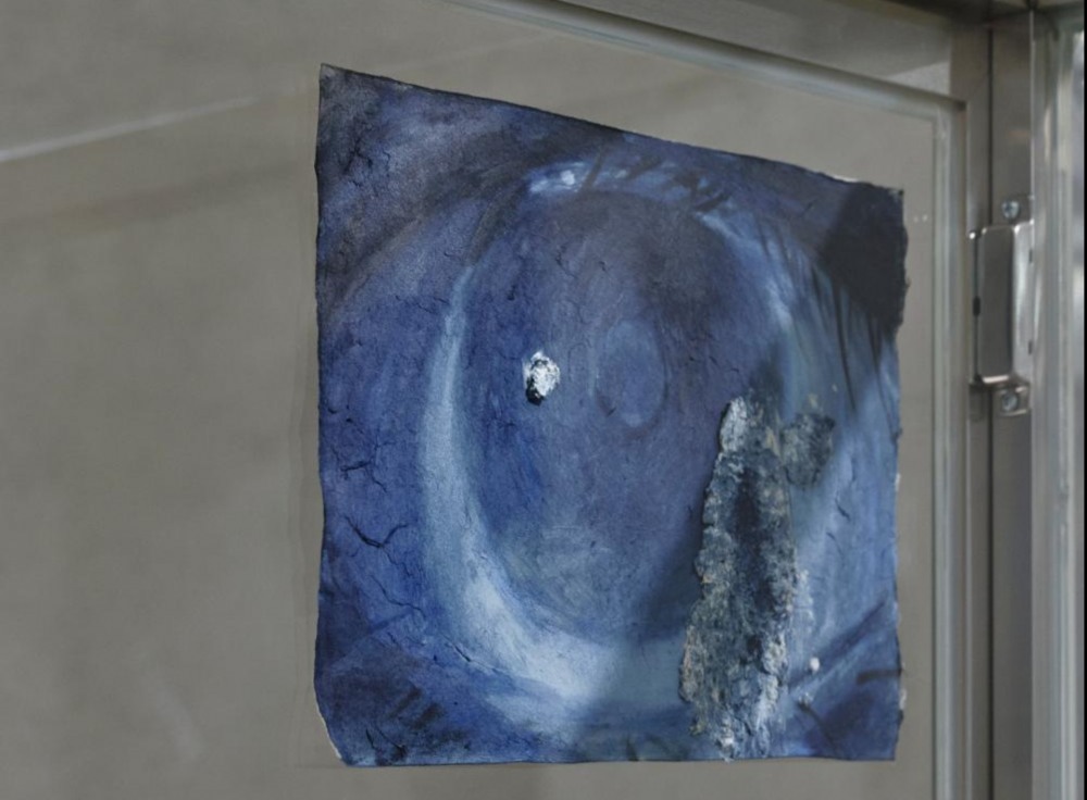 〈아무것도 모르는 것처럼 또는 의식하지 않는 것처럼〉, 2024, 스테인리스 스틸 프레임의 유리 상자, 발견된 의자, 버려진 감시 카메라, 한지, 종이 풀, 나무, 책, 이어폰, 버려진 청바지, 운동화, 모니터, 종이, 사진, 끈, 160×120×70cm.