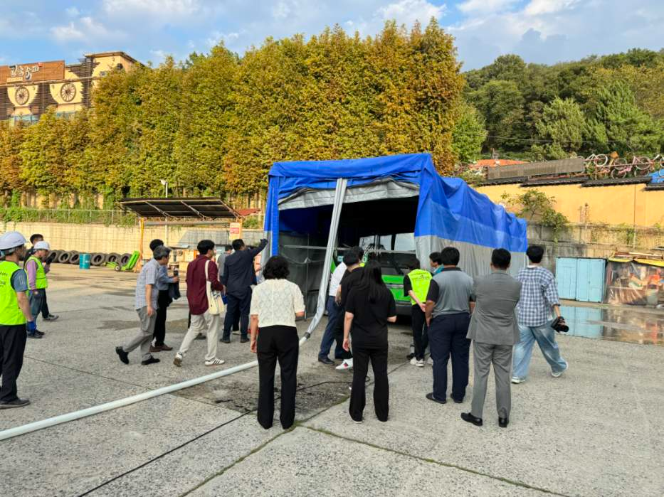 안양시가 지난 25일 버스공영차고지에서 실시한 자동식 질식소화포 시연 및 훈련에 참여자들이 소화수가 연결된 내부 모습을 살펴보고 있다