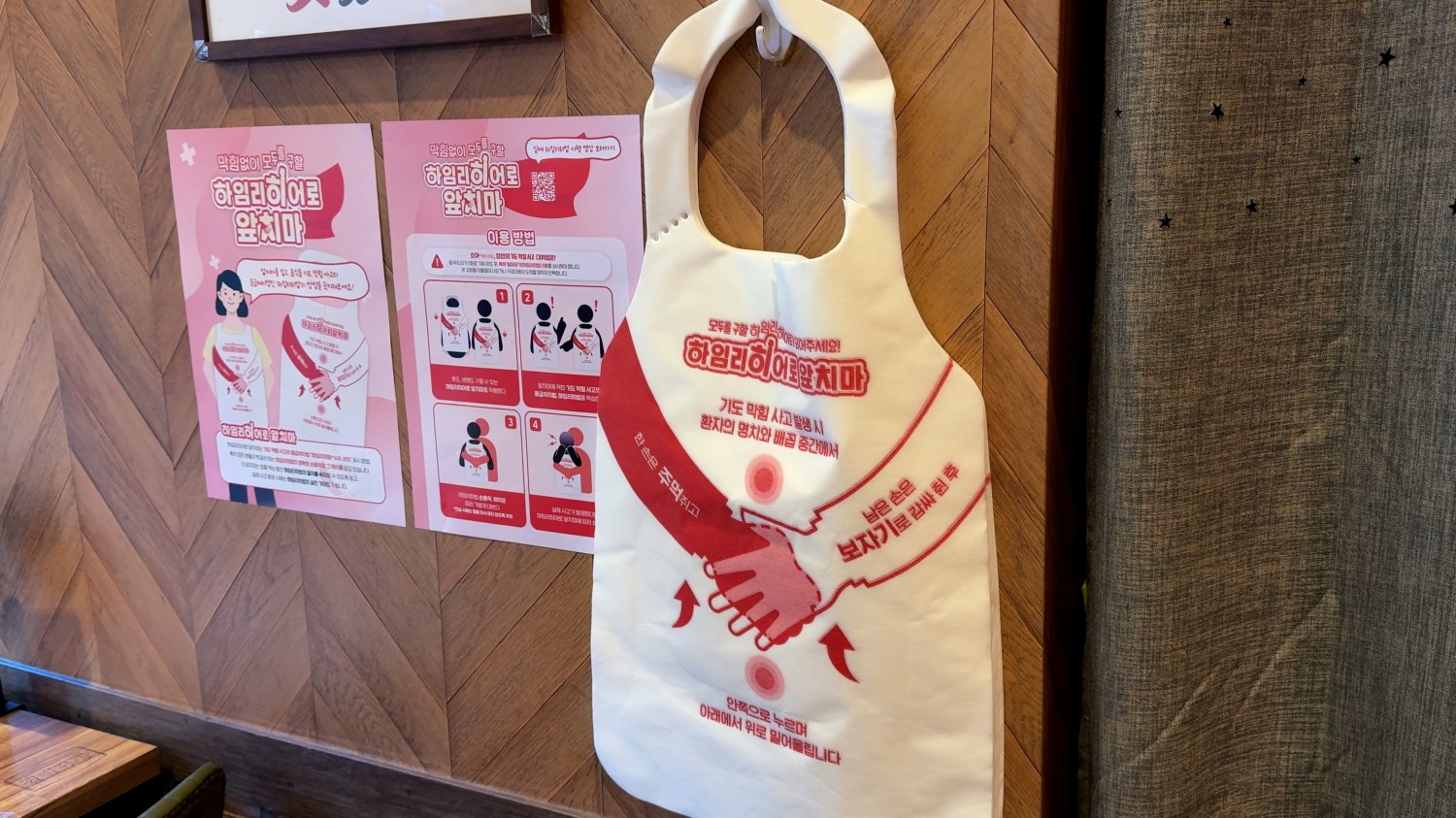 하임리히법의 시행 방법이 담긴 하임리히어로 앞치마가 캠페인 설명 포스터 2종과 함께 협업 음식점 ‘청년다방’에 걸려있다.