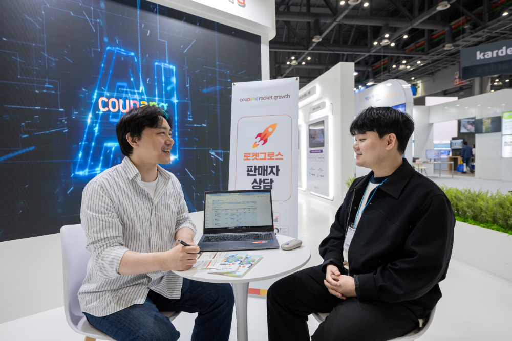 2025 물류산업대전 행사장에 설치된 쿠팡 부스에서 한 관람객이 로켓그로스 입점 상담을 받고 있다