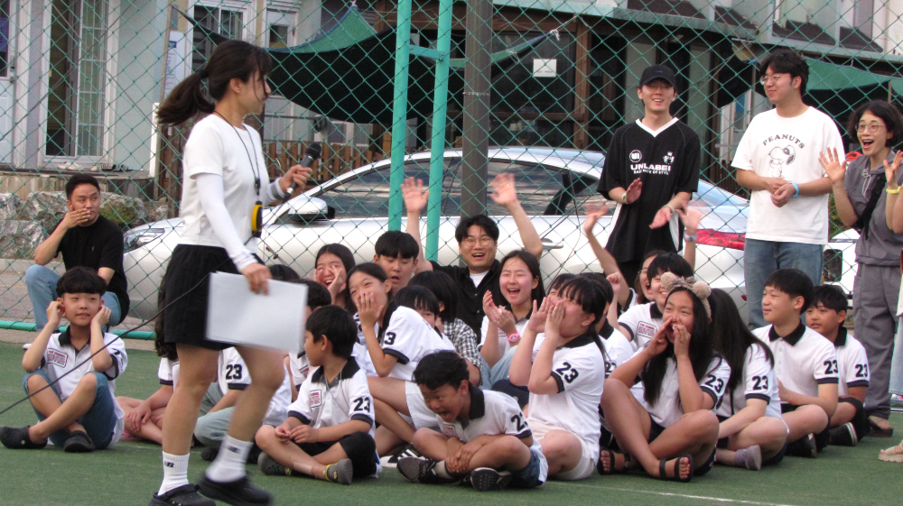 여름방학 캠프 현장에서 사회자의 진행에 맞춰 아동·청소년들이 앉아 환호하고 웃으며 즐겁게 참여하고 있다./사진=HR그룹(주) 미디어팀 제