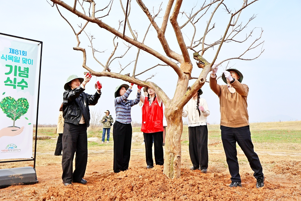 하림 임직원 및 행사 참여자들이 새만금환경생태단지에 나무를 식재한 후, 친환경 소재를 활용해 제작한 수목 이름표를 나무에 직접 걸어주는 체험 활동을 하고 있다.
