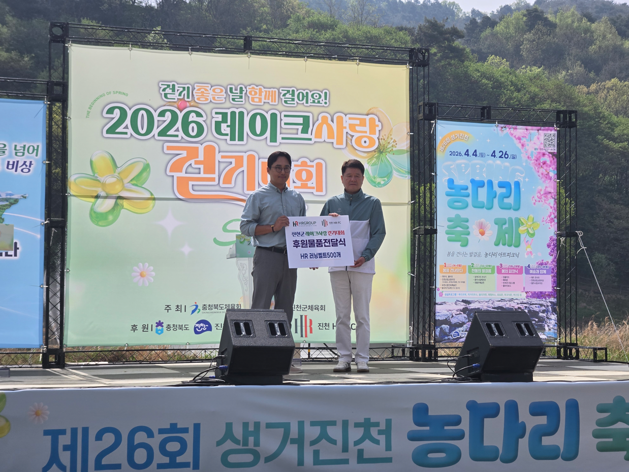 ‘2026 레이크 사랑 걷기 대회’ 현장에서 신호룡 진천 HR FC 구단주(왼쪽)가 김화영 진천군 체육회장(오른쪽)에게 후원 물품 전달식을 진행하며 기념 촬영을 하고 있다./사진=HR레포츠㈜ 제공