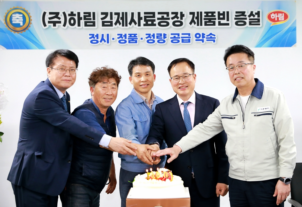 22일 열린 ㈜하림 김제사료공장 제품빈 증설 행사에서 주요 임직원 및 관계자들이 축하 케이크 위로 손을 하나로 모으며 성공적인 증설 완공과 사육농가를 향한 '정시·정품·정량 공급'을 약속하고 있다. (사진=하림)