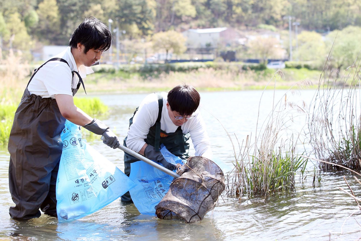 신천지자원봉사단 대전지부 봉사자들이 지난 16일 서구 정림동 갑천 국가 습지보호지역에서 환경정화 활동을 통해 수거한 쓰레기를 나르고 있다. / 사진 제공: 신천지자원봉사단