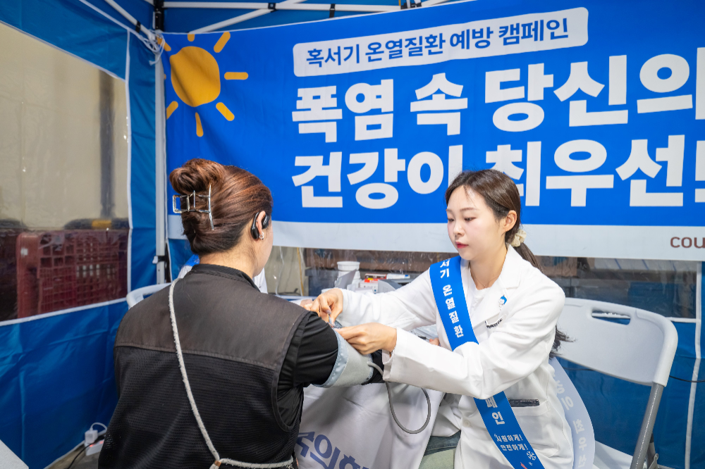 KMI 의료진이 일산1캠프에 입차한 위탁배송기사의 혈압을 측정하고 있다