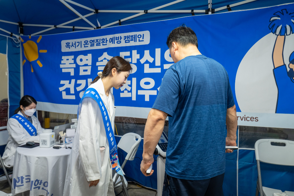 KMI 의료진이 일산1캠프에 입차한 위탁배송기사의 체성분 측정을 안내하고 있다